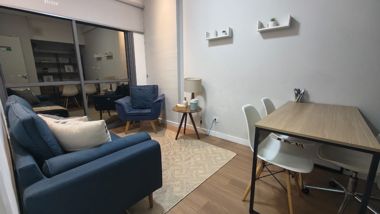 Sala 2 mobiliada com sofá azul, poltrona, mesa de trabalho e cadeiras